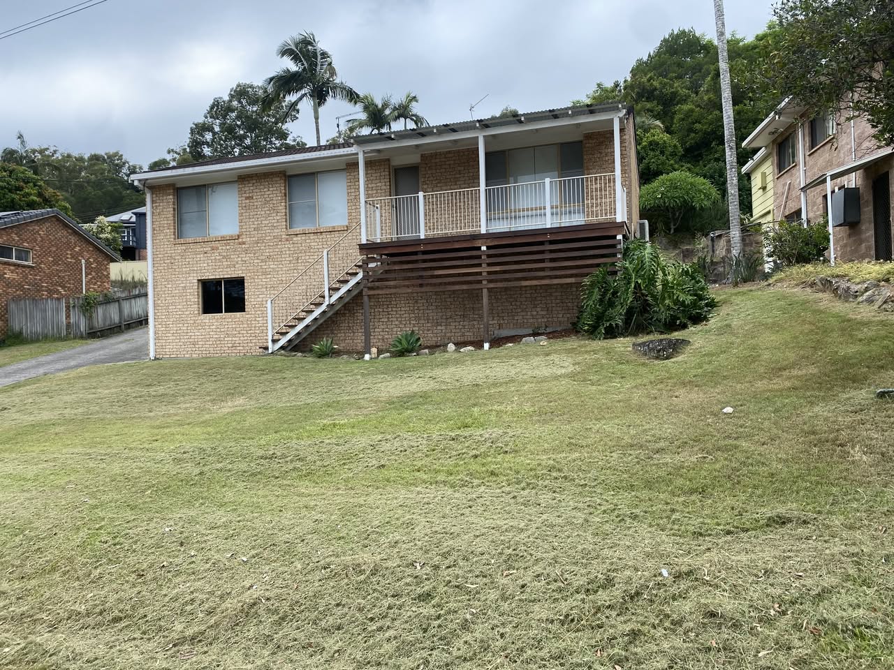 Same property after the mow — neat short grass, deck edged, cuttings raked off.